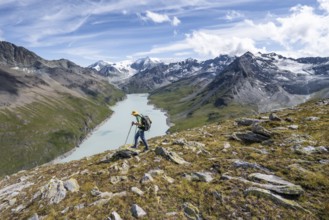 Mountaineer on the summit of Mont de la Blana, view of a blue mountain lake, Lac des Dix reservoir,