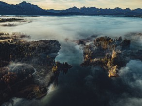 Autumn sunrise in the foothills of the Alps with fog at Illasbergsee and Forggensee near Halblech