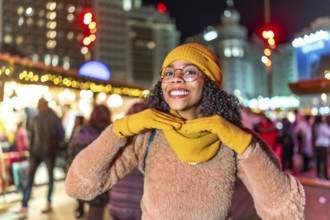 Young woman dressed in vibrant yellow winter attire, enjoying the festive atmosphere of a bustling