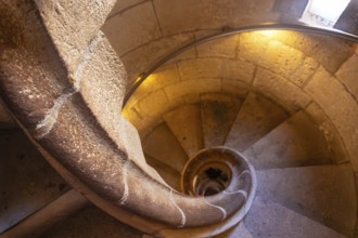 Warm light illuminating ancient stone spiral staircase descending into the depths of barcelona