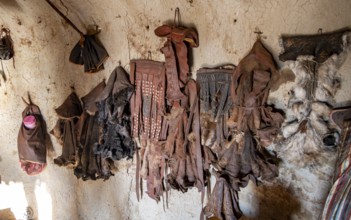 Various traditional leather aprons hanging on the wall, interior of a mud hut of the first woman in