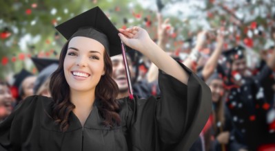 Young female graduate celebrating her graduation with her fellow classmates outdoors