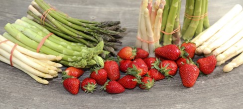 Green asparagus, white asparagus and fresh strawberries decorated on a rustic wooden table