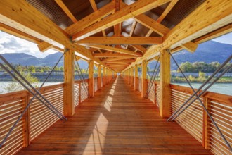 Symmetrical interior view of a wooden bridge with a view of the river and mountains, Inn