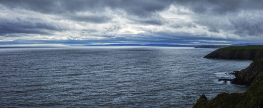 Gloomy panorama of the coast under a heavy, cloudy sky, Waterford Coast
