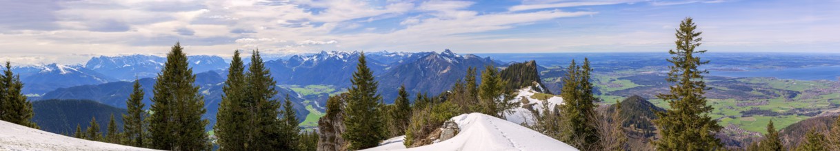 Panoramic view over the snow-covered Chiemgau mountains with forest and clear blue sky in the