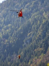 2 mountain rescuers of the Bavarian Mountain Rescue Service are winched by the on-board mechanic of