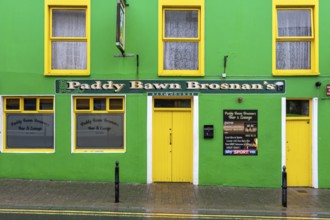 A green-painted pub façade on the roadside, Dingle