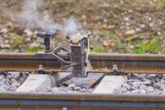Metal fixture on the rails with rising smoke, rural environment, rail welding, track construction