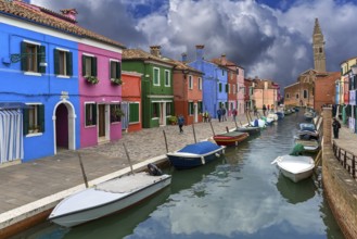 Colourful houses on the canal, behind the leaning tower of the church of St. Martin Vescovo, 16th