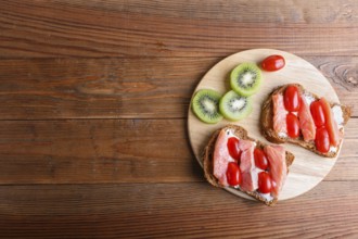 Smoked salmon sandwiches with butter on wooden background. cherry tomatoes. top view, copy space