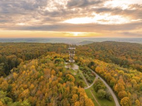 Majestic tower amidst a vibrant autumn forest under a dramatic sunset sky, Schönbuchturm,