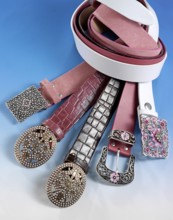 Various belts in front of a blue background, studio shot