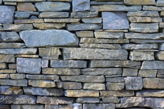 Large, irregular natural stones in various shades of grey form a rustic stone wall, Bergen,