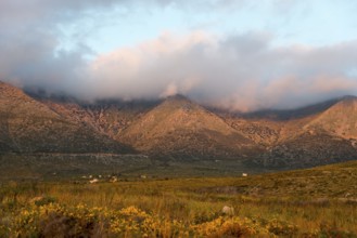 Mountain landscape at dusk with clouds enveloping the peaks in a tranquil rural setting, Itylo,