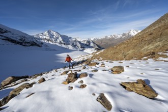 Mountaineer on a hiking trail with snow, descent from Ramoljoch at Spiegelferner, autumnal mountain