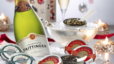 Champagne bottle, caviar, caviar tins, decorated with burning candles, studio shot