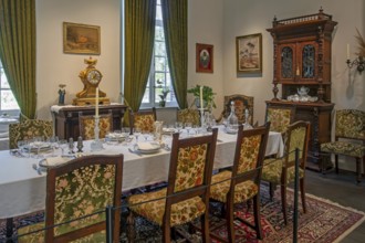 Dinner table with antique tableware in dining room inside 18th century clergy house Schriek at open