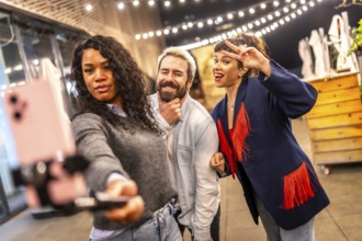 Friends gesturing success while streaming online video with smartphone during party at night