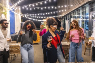 Group of young multi-ethnic friends dancing and drinking at outdoor night party
