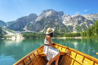 Young woman admiring the stunning landscape of lake braies from a wooden rowboat, surrounded by