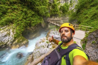 Tourist wearing helmet and backpack hiking in vintgar gorge, near bled, slovenia, making thumbs up
