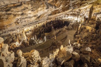 Tourists walking on illuminated footpath inside the famous postojna cave, a karst cave system near