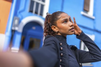 African american woman posing while taking selfie in the city next to blue colorful houses