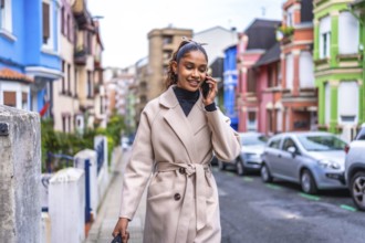 Stylish and beauty african american businesswoman wearing trench coat talking to the mobile phone