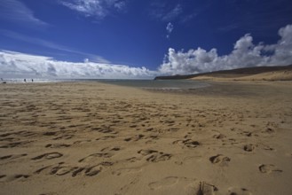 Beach Playa Risco del Paso, Playa de Sotavento with footprints in front of a cloudy blue sky,