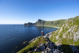 Mountaineer with view of coastal landscape, steep coast with peak Måtind, Høyvika beach and sea,