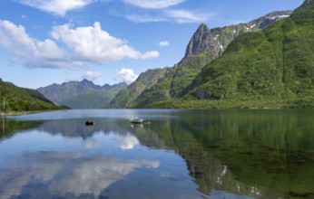 Small boats at the fjord Austnesfjorden, idyllic Norwegian fjord landscape, mountains reflected in