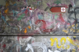 Graffiti-covered concrete wall with Olav's Cross signposting for pilgrims on the Olav Trail or