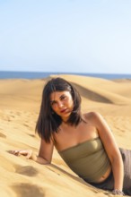 Young woman lying on the sand in the maspalomas dunes, gran canaria, canary islands, spain,
