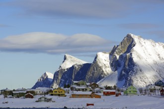 Colourful houses on snowy hills and mountains under a blue sky with few clouds, peaceful winter