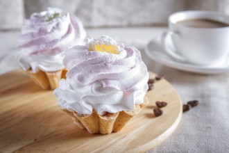 Cakes with whipped egg cream on wooden board, selective focus, close up