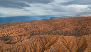 Landscape of eroded hills, badlands at sunset, Issyk Kul Lake in the background, aerial view,