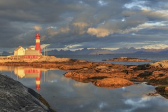 Lighthouse reflected in water, morning light, clouds, mountains, coast, Tranoy, Ofoten, Norway,