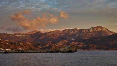 Impressive coastal scene at sunrise with mountains and dramatic clouds in the sky, Pigadia, town