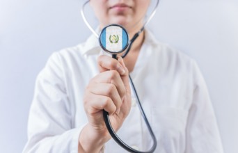 Female doctor holding stethoscope with Guatemala flag. Guatemalan Health and Care concept