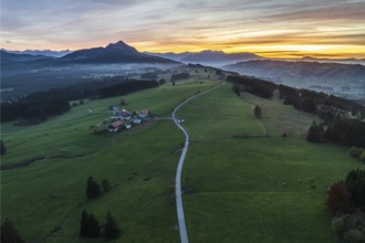 Mountain range near village Wertach, view to mt. Gruenten, sunset, fog in valley, traditional farm,
