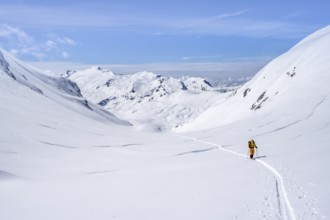 Lone ski tourer in a mountain landscape with snow, summit Wildhorn in the background, ascent to