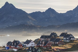 Typical Greenlandic houses on a fjord with steep mountains, Inuit settlement, autumn, Tasiilaq,