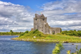 An old castle on a green meadow by the water under a cloudy sky, Dubguaire Castle