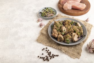 Stewed turkey fillet with garlic and sprouts of radish on white wooden background and linen textile