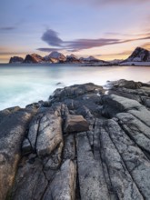 Rocky coast, snow-capped mountains in the background, Vestvågøya, Lofoten, Norway, Europe