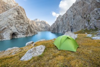 Green tent at the turquoise mountain lake Kol Suu with rocky steep mountains, Kol Suu Lake, Sary