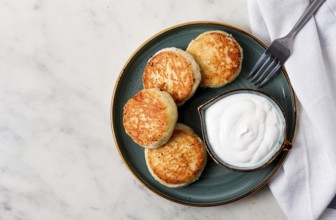 Fried, Cottage cheese pancakes, with sour cream, Cheesecakes, on a marble table, top view, no