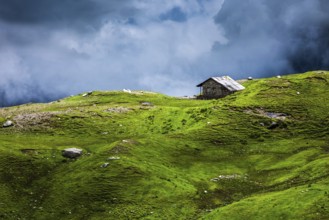 Serenity serene lonely scenery background concept, house in mountains on alpine meadow in clouds.
