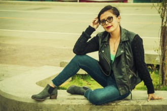 Portrait of beautiful latin girl sitting on a bench. attractive young woman with glasses sitting on